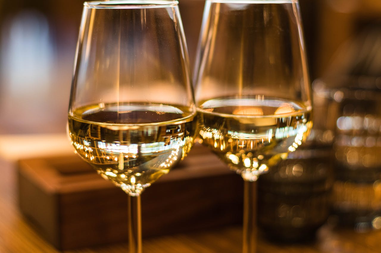 Contact Two elegant wine glasses filled with white wine, captured with a beautiful bokeh effect.